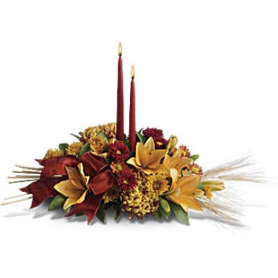 Add a graceful glow to your Thanksgiving dinner table or fall-decorated foyer with this warm, seasonal arrangement. Lilies, mums and asters are accented with sprays of wheat below glowing taper candles.
This classic Thanksgiving centerpiece features orange asiatic lilies, red matsumoto asters, bronze disbud mums, bronze daisies and bronze cushion mums.
Burgundy satin ribbon, stems of wheat, and two taper candles add seasonal sophistication.