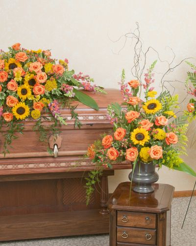 Includes a casket spray, standing spray and urn design in the warm colors of a sunset.