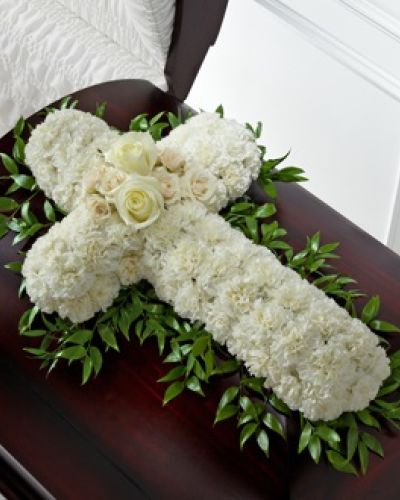 The FTD® Peaceful Memories™ Casket Spray is a gorgeous way to commemorate the faith and devotion of the deceased. White carnations are arranged in the shape of a cross accented in the middle with white roses and spray roses and along the sides with lush greens to create a lovely casket spray that brings peace and solace to those that attend their final farewell.