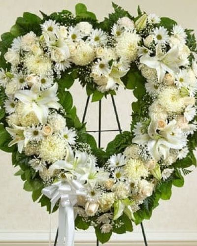 Celebrate a beautiful life while expressing your most heartfelt sympathy. This exquisitely crafted, heart-shaped wreath is hand-arranged by our expert florists using the freshest white blooms to create a touching tribute to a special loved one who has passed. The arrangement features fresh white roses, lilies, carnations and more accented by baby's breath, salal and leather leaf and finished off with a satin ribbon. Traditionally sent directly to the funeral home by family members or friends and displayed on a stand.
