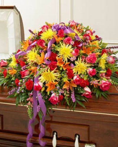 Send an elegant expression of your love and a touching tribute to a loved one with this bright casket cover arrangement. Features gorgeous bright blooms such as long-stem roses, lilies, spider mums, larkspur, carnations, monte casino and more. Traditionally sent by the immediate family to the funeral home.