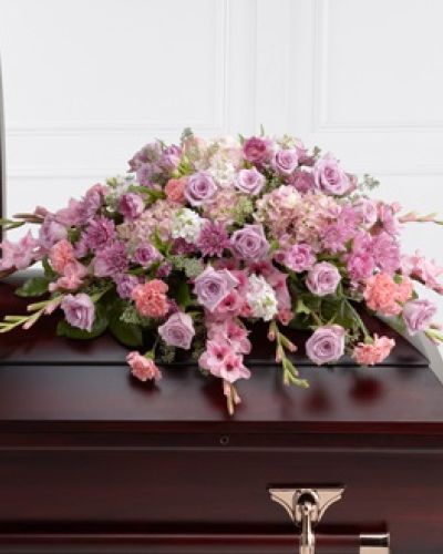 The FTD® Immorata™ Casket Spray offers soft beauty and blushing comfort to honor the life of the deceased. Lavender roses, chrysanthemums and parrot tulips are elegantly arranged amongst pink carnations, gladiolus, stock, hydrangea and lush greens to create a presentation, intended to bedeck the top of the casket, that evokes sweet memories of your loved one for their final farewell service.
