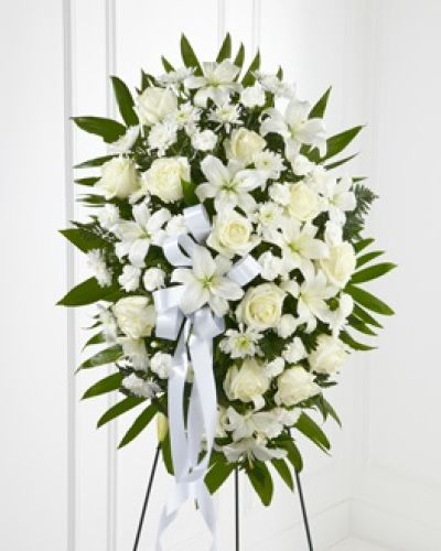 The FTD® Exquisite Tribute™ Standing Spray is an elegant display of sweet serenity. White roses, Asiatic lilies, chrysanthemums and mini carnations are artfully arranged amongst emerald palm fronds and lush greens. Accented by white satin ribbon and standing on a wire easel, this standing spray is an outstanding way to honor the life of your loved one.