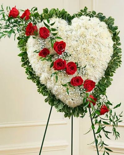 This beautiful floral tribute shows your undying love during this difficult time. This standing spray arrangement in the shape of a heart is created from fresh white carnations, red roses, baby's breath and more. Traditionally sent directly to the funeral home by family members or friends and displayed on a stand.