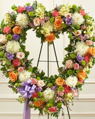 During times of loss, words are not always enough to convey all the sympathy you feel in your heart. Skillfully arranged by our expert florists, this open-heart floral tribute is a fitting expression of your condolences. Crafted using delicate pastel-colored blooms, this heart-shaped arrangement features delicate pastel-colored blooms including fresh peach and pink roses, mums, stock, carnations, lisianthus and heather accented by salal, leather leaf and more. Traditionally sent directly to the funeral home by family members or friends and displayed on a stand.
