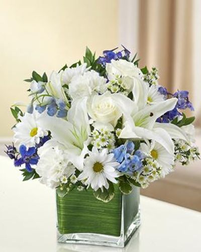 Send your best wishes with our blue and white Hope Floats arrangement. The freshest roses, delphinium, lilies, daisy poms and carnations are hand-designed in a stunning cube vase sure to wow and inspire your recipient.
