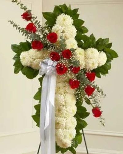 This beautiful floral tribute shows your faith, hope and love during this difficult time. This standing spray arrangement in the shape of a cross is created from fresh white mums, red roses, spiral eucalyptus and more. Traditionally sent directly to the funeral home by family members or friends and displayed on a stand.