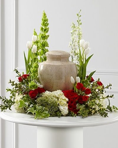 The FTD® Tears of Comfort™ Arrangement is an elegant and sophisticated way to surround their urn with floral beauty at the final farewell service. Rich red roses and spray roses are vivid and bright arranged amongst white tulips, larkspur, hydrangea, and trachelium, accented with the bright greens of Bells of Ireland, hypericum berries, ivy and myrtle, creating a wonderful way to honor the life of the deceased.