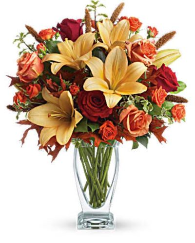 Roses, lilies and oak leaves create a fantasy of fall flowers. Send this tall, elegant arrangement to wish someone a happy autumn or joyous Thanksgiving. The warm color palette and Couture Vase make a stylish seasonal statement.
Orange, dark orange and red roses blend with orange asiatic lilies, green salal and pitta negra. Subtle seasonal elements include dried oak leaves and millet.