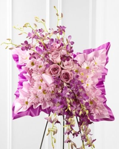 The FTD® Simply Restful™ Floral Pillow is a gorgeous display of soft serenity. Lavender daisies, purple dendrobium orchids and lavender roses are beautifully arranged against a bed of purple and lavender satin to create a stunning presentation. Displayed on a wire easel, this arrangement bursts with grace and elegance to honor the life of the deceased.